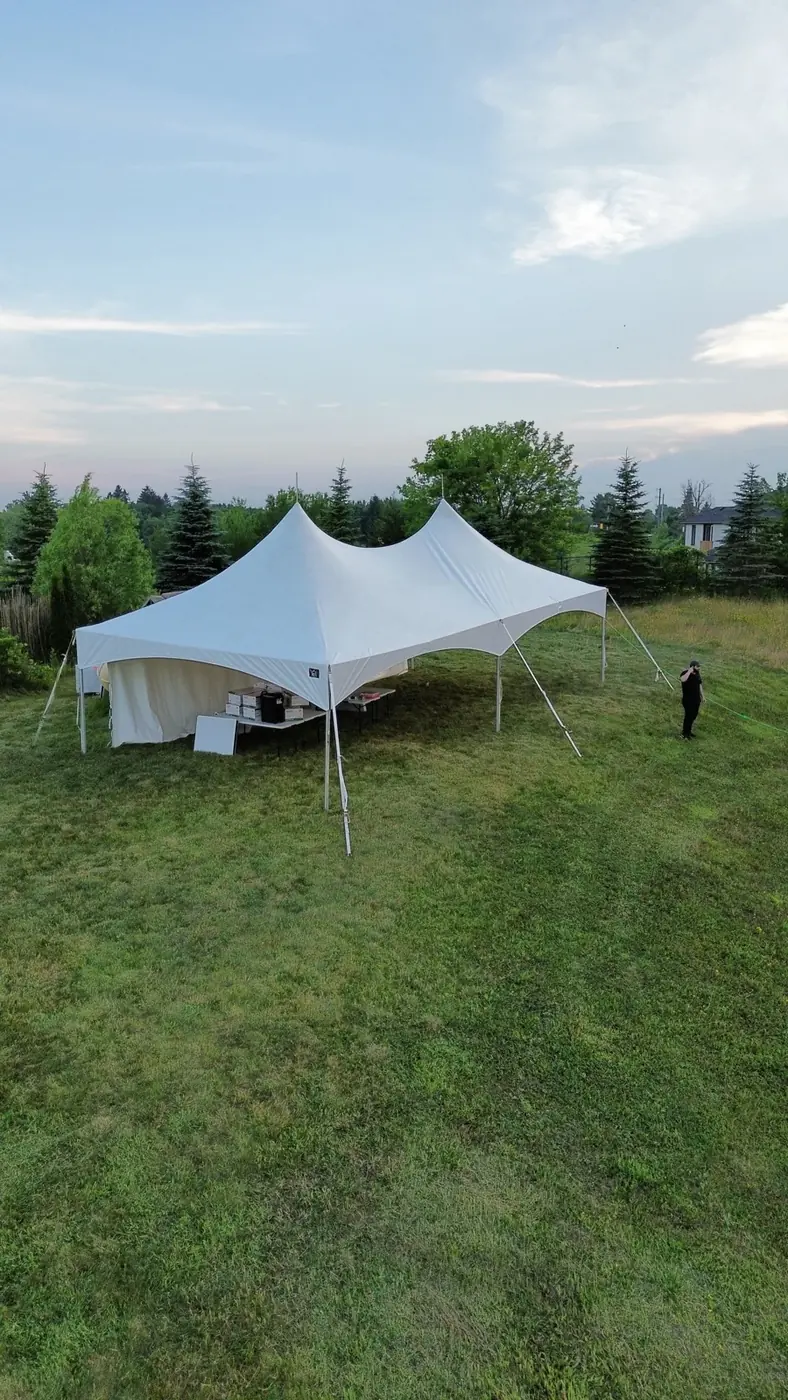 White event tent with guest seating and dining tables arranged beneath the canopy