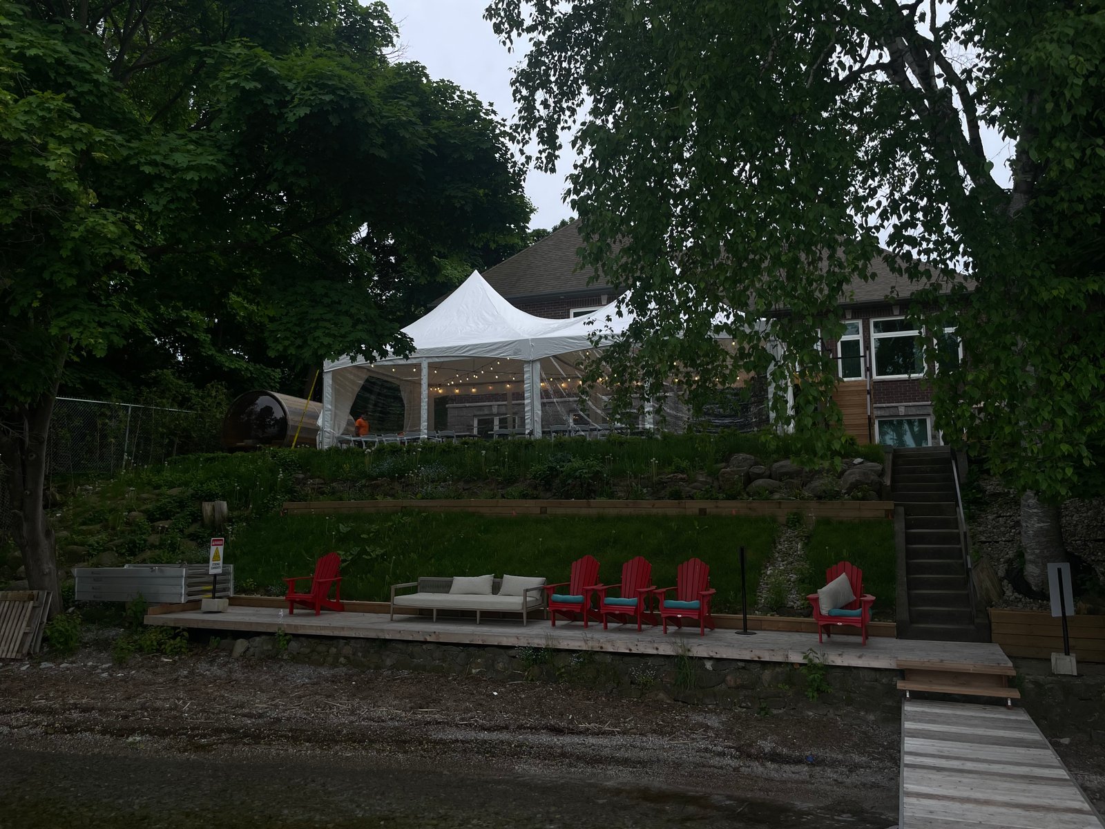 White event tent set up on a lawn beside the water