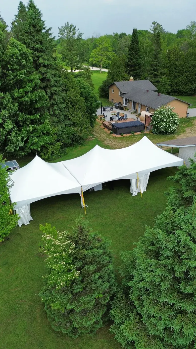A large white tent beside a Caledon home with a spacious green backyard