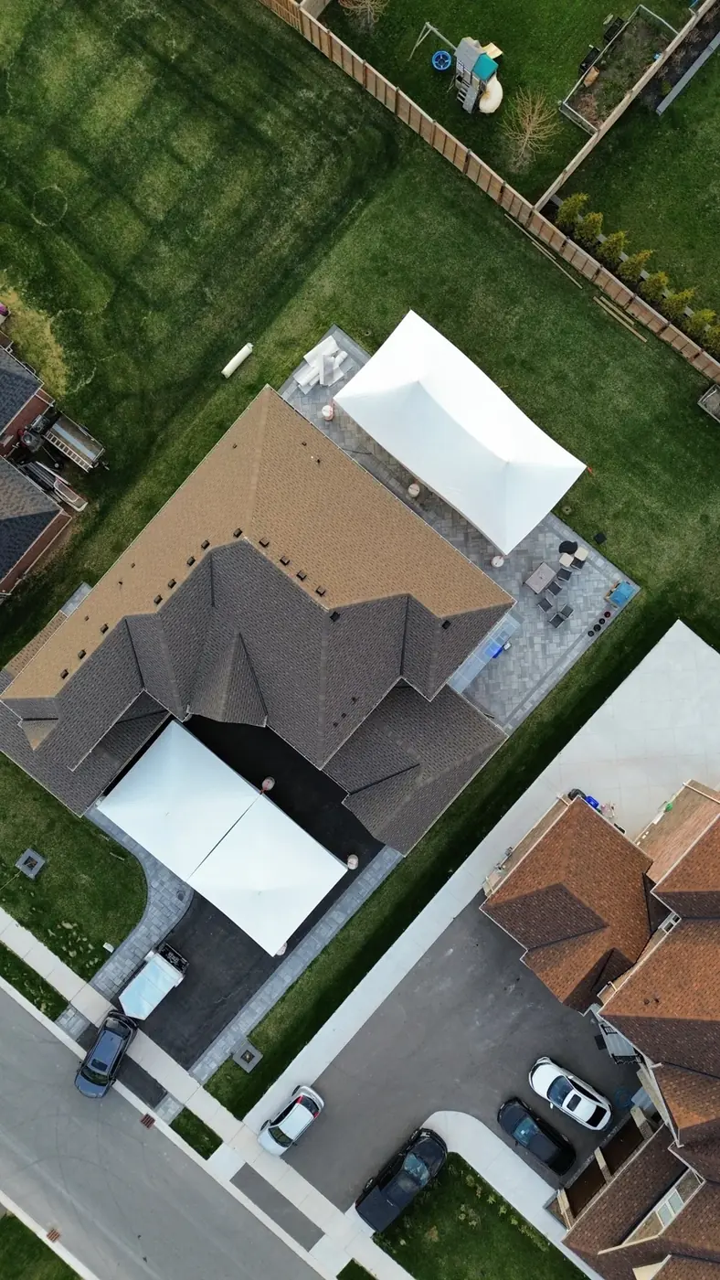 Two white event tents arranged across a driveway and backyard